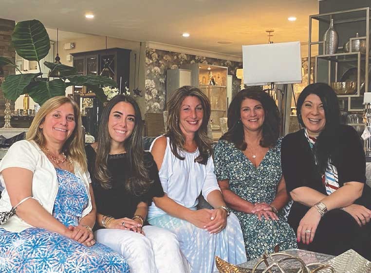 5 women sitting on a couch, smiling at the camera